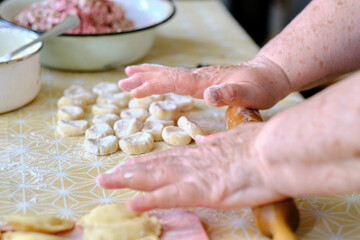 Rolling out dough with rolling pin and hands for cooking dumplings.