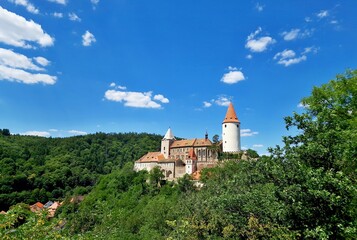 Krivoklat castle in middle Bohemia, Czech Republic. A panoramic view of famous castle Krivoklat against blue sky with white clouds in forest country. Medieval castle Krivoklat was built in 12th centur