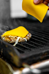 man hand cooking cheeseburger on grill
