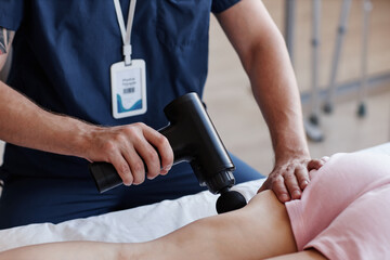 Naklejka premium Close-up of therapist using medical massager to do massage to patient in hospital