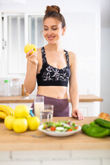 Obraz premium Slender sports girl eating apples in kitchen during breakfast