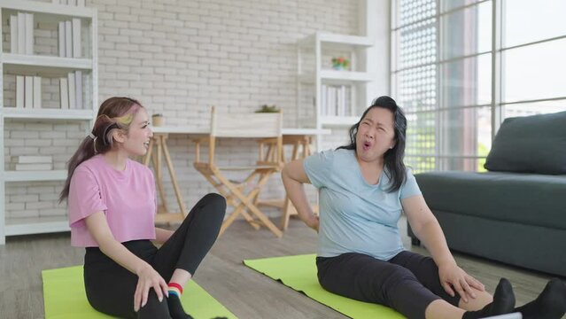 Elderly asian mother having back pain while exercise training with daughter at home. Elderly woman having problem with suffer backache painful from exercising. Elderly health problems