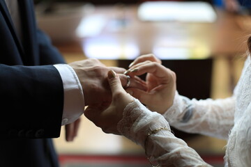 Die wunderschöne Braut steckt einen goldenen Hochzeitsring an den Finger des Bräutigams