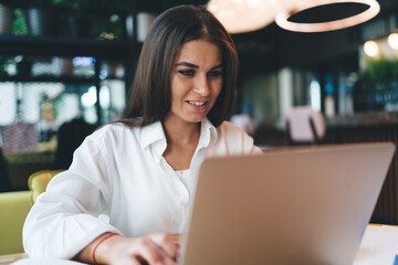 Cheerful woman working on startup project on laptop