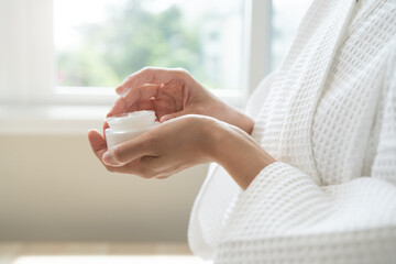 Close-up woman using skin care serum cream in daily routine.