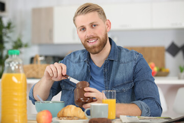 handsome casual man having breakfast at home
