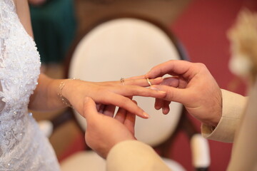 Bräutigam steckt einen goldenen Hochzeitsring an den Finger des Braut.