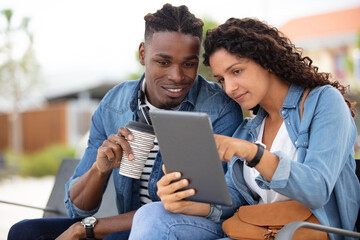 young couple playing games in a tablet at train station