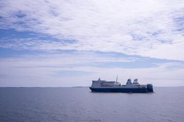 Cargo ship in the sea with blue sky and white clouds.