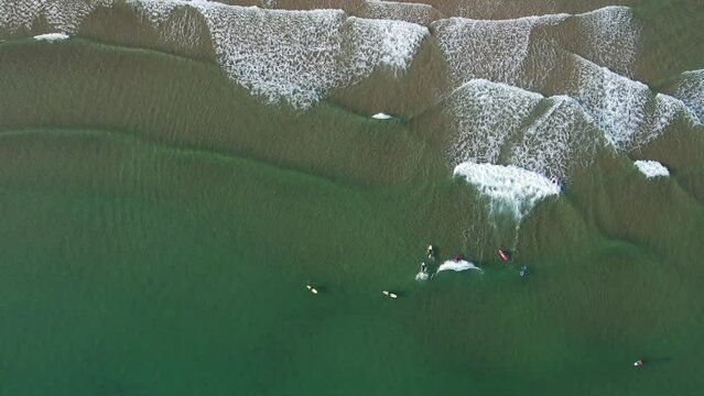 Aerial view of a group of surfers catching waves in the Costa Verde northern Spain