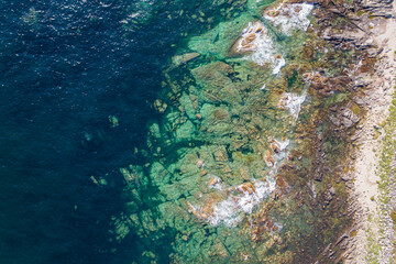 aerial top view of a rocky beach with turquoise waters at sunrise