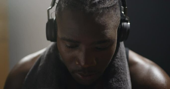 Music, black man athlete with headphones and at a gym or sports team club. Fitness or motivation, prepare for exercise or training and African male boxer with headsets for meditation or mindfulness - Powered by Adobe