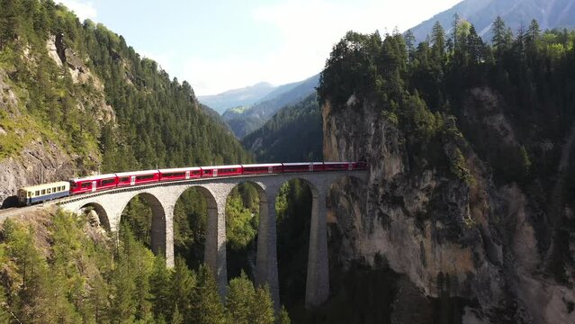 Aerial video of a red panoramic train on the bridge in the Swiss village of Longran, Switzerland