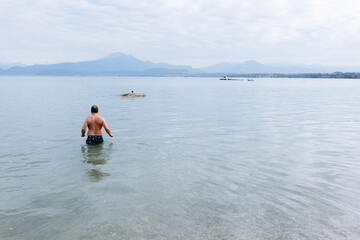 Fototapeta na wymiar rear view of man entering water to swim in the lake