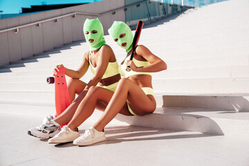 Two beautiful sexy women in green underwear. Models wearing bandit balaclava mask. Hot seductive...