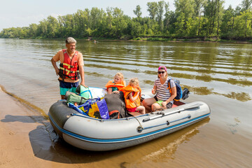 tourist family floats on an inflatable boat in life jackets on a summer day
