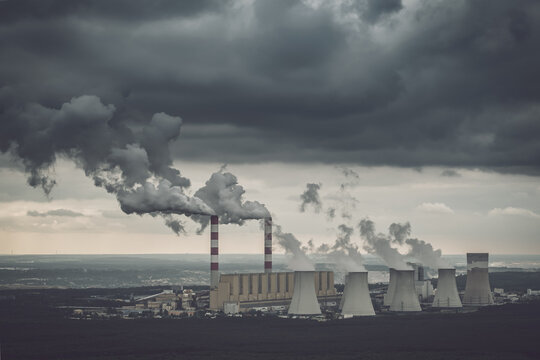 Aerial view of power plant, smoke from chimneys and open-cast coal mine in Belchatow under moody cloudy sky, Poland