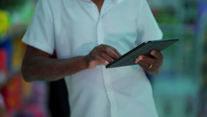 Close-up of a senior black man hands holding tablet device. Elderly person hand detail engaged with modern technology
