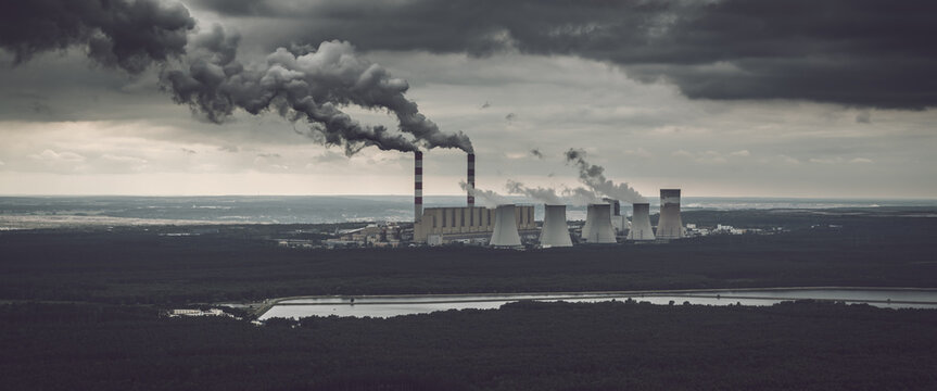 Aerial view of power plant, smoke from chimneys and open-cast coal mine in Belchatow under moody cloudy sky, Poland