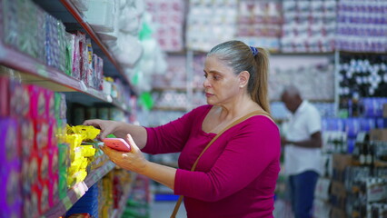 Consumer picking item from grocery store shelf while looking at item details on cellphone device, inspecting ingredients
