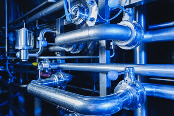 Pipes stainless steel brewing equipment, large reservoirs or tanks in modern beer factory. Brewery production concept, industrial blue background