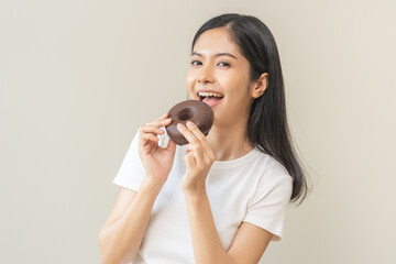 Portrait of pretty hungry asian young teenage woman hand holding sweet chocolate donut, eating doughnut, happy beauty female, girl emotion enjoy when eat dessert. Isolated over background, copy space.