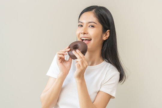 Portrait Of Pretty Hungry Asian Young Teenage Woman Hand Holding Sweet Chocolate Donut, Eating Doughnut, Happy Beauty Female, Girl Emotion Enjoy When Eat Dessert. Isolated Over Background, Copy Space.