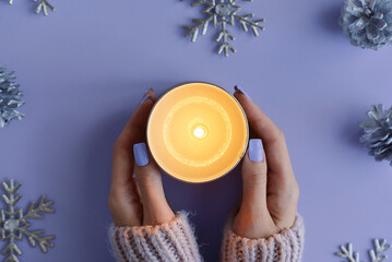 Female's hands with purple manicure holding a burning soy candle. Winter season concept, top view - 627737083