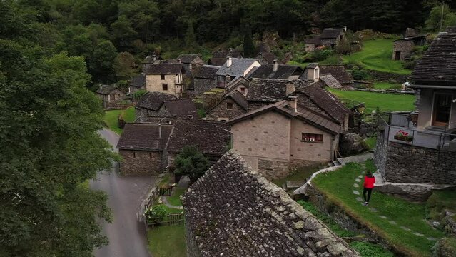 Aerial video of a man with a red coat walking in Cevio, Switzerland