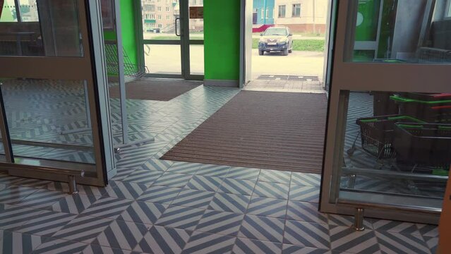A woman with a grocery cart enters a store