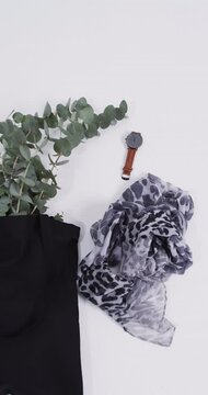 Vertical video of black canvas bag with plant, scarf, watch, copy space on white background