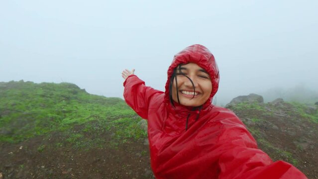 4K portrait of young Indian woman travel vlogger vlogging while trekking on Sahyadri mountains, India. Social media influencer hiking during rain in monsoon season.