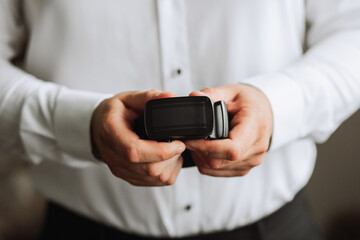 a man holds a black belt in his hands, close-up photo. The groom is preparing for the wedding ceremony