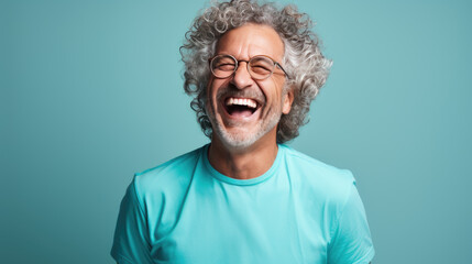 Middle-aged man laughs against a blue background.