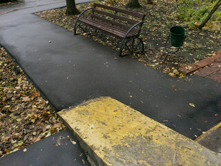 A small courtyard in a large metropolis. A wheelchair access ramp and a sidewalk are visible. The view is slightly from above