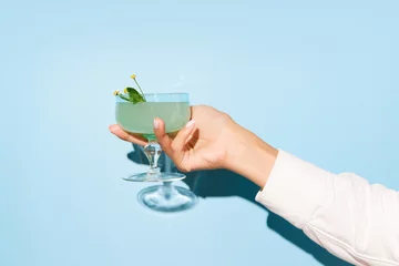 Foto op Plexiglas Women hand holding glass with margarita cocktail on light blue pop art background. Copy space for ad. © Lustre