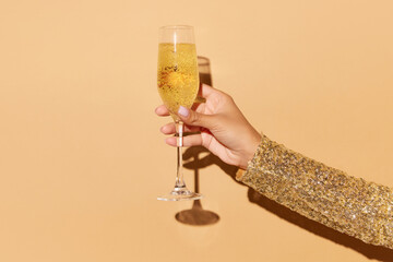 Lady's hand holding glass of shampange with lime and bright straw on light blue background.