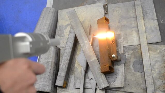 Laser cleaning of metal. Industrial removal of rust of metal surface with laser beam. Man cleaning surface from corrosion with laser metal cleaning machine. Industrial laser cleaning rust of metal.