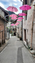 Fototapeta na wymiar Des parapluies roses en décoration dans une rue piétonne de Chanaz dans le département de la Savoie en France