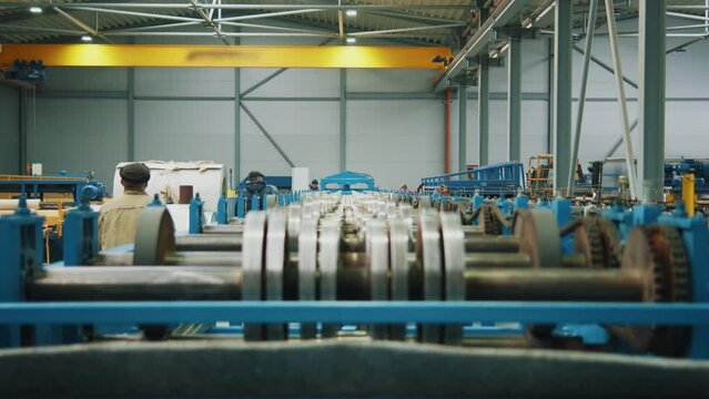 Close up metal sheet forming machine in metalwork factory. Steel rollers in metalforming machine for production roof tile in factory