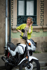 Obraz na płótnie Canvas A woman wearing headphones stands next to a sportbike.