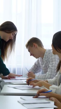 Vertical Screen: Young caucasian teacher check and control college students knowledge and skills in classroom. practice, learning, education, knowledge, development, growth concept
