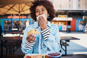 Woman wiping her mouth with a napkin while eating tacos on a restaurant patio