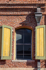 Red Brick Building with Yellow and Green Wooden Shutters.
