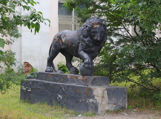 An old broken abandoned lion statue in the roadside bushes, Obukhovskaya Oborona Avenue, Saint...