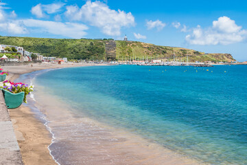 Turquoise water of the bay of Praia da Vitória with marina and hill with the Facho viewpoint in...