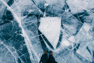 Traveler's feet standing on the frozen ice of Lake Baikal