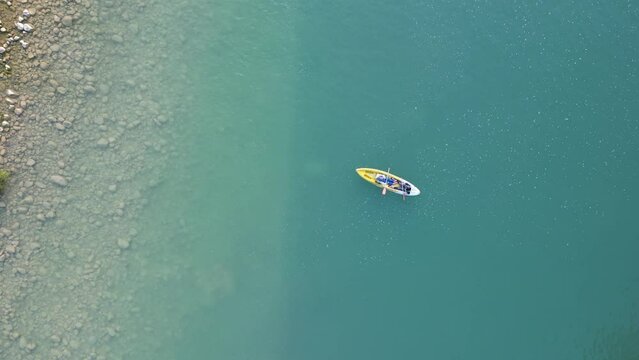 Aerial view of canoe boats in mountain river with turquoise water with rock cliffs. People kayaking, canoeing, and swimming in Kedung Jati Parang, Selopamioro, Imogiri, Bantul, Yogyakarta. 4k footage