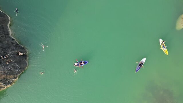Aerial view of canoe boats in mountain river with turquoise water with rock cliffs. People kayaking, canoeing, and swimming in Kedung Jati Parang, Selopamioro, Imogiri, Bantul, Yogyakarta. 4k footage