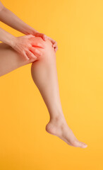 Address knee pain and healthcare with woman's hands holding her painful knee on a vibrant yellow background. Relief and wellness concept.
